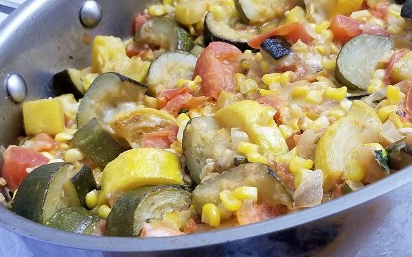 After the squash has simmered for 15 minutes, add in the cooked corn, shredded cheese and oregano.