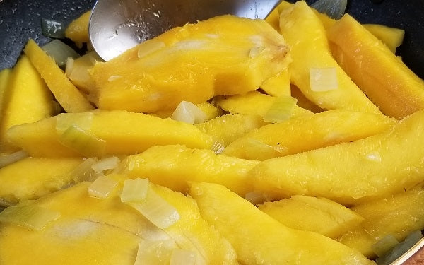 Peel and pit the mangoes, cut them into long slices. Sauté onion in olive oil until translucent, then add the mango slices and continue the sauté. 