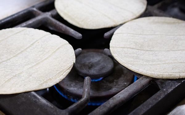 Take the corn tortillas, one at a time, and heat over an open flame/gas burner about 15 seconds per side.