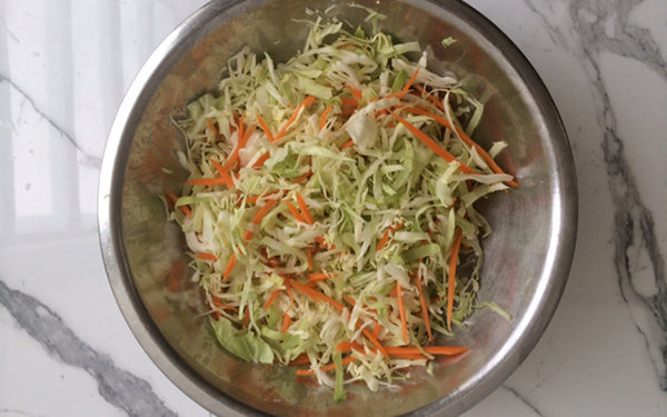 In a large bowl, add cabbage and carrots. Pour hot dressing over veggies and toss to combine.