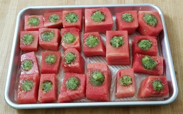 Place watermelon cubes on a cookie tray lined with parchment paper, then fill each cup with kiwi purée. 