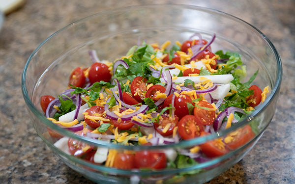 In a large mixing bowl, combine the lettuce, tomato, onion, jicama, cheese and cilantro.