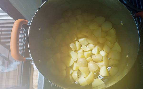 Cut potatoes into quarters (about 1/2-inch pieces) and place in a large bowl.