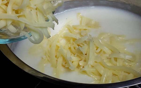 Image of Remove pan from flame, stir in milk. Return to flame and bring to a slow boil, then reduce heat and simmer for 3 minutes. Stir in cheese, salt and pepper to taste, and set aside