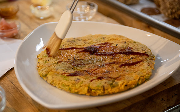 Transfer okonomiyaki onto plate. Drizzle with okonomiyaki sauce and mayonnaise. Sprinkle with ground bonito flakes, slivered ginger and cilantro or green onion. Cut into wedges and serve immediately.