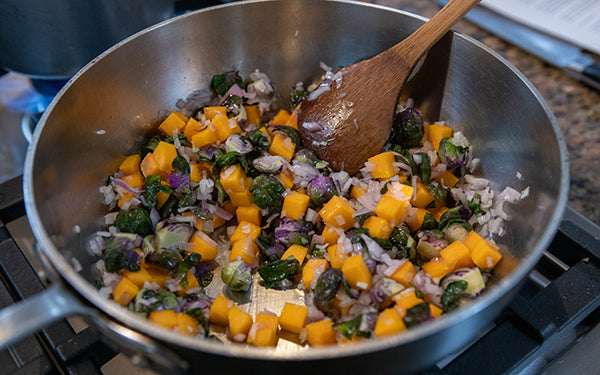 Heat the olive oil in a large sauté pan, and then add the shallots, butternut squash, and purple Brussels sprouts. Add a couple of pinches of sea salt and fresh ground black pepper, then stir and cook over medium-high heat for five minutes.