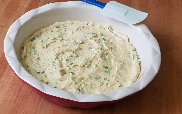 In a large mixing bowl, whisk together the melted butter, cream, and eggs. Then add in the green chile, both flours, agave, salt, baking soda and stir well to combine. 