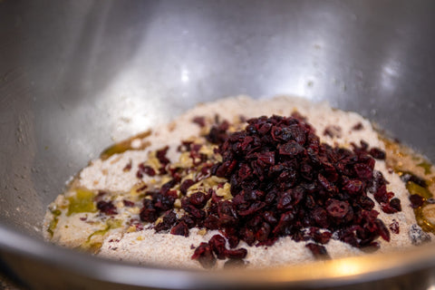 Image of dried cranberries, flour and oil mixture in a mixing bowl