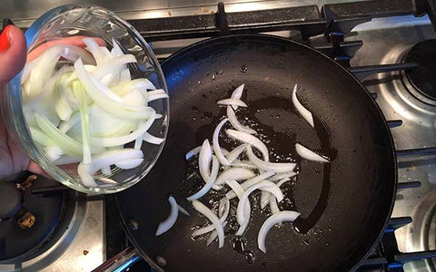 Image of Heat a large nonstick sauté pan over medium heat. Add oil and then the onion (and shishitos if using). Sauté for two to three minutes or until the onion has softened but not browned