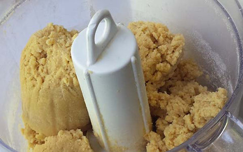 Image of Drop in soft pieces of butter while the processor is running; as the batter becomes a ball, add in rest of the coconut flour