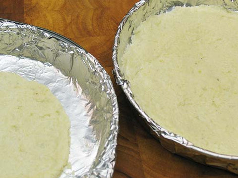 Image of pizza dough patted into pie pans