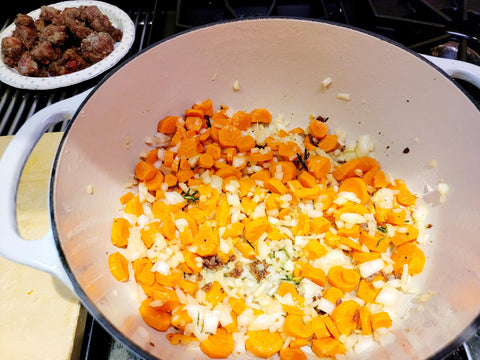 Image of Add rosemary, carrots, onions and mushrooms to the Dutch oven and stir with a wooden spoon several times to release the fond on the bottom of the pot (brown bits that hold flavor). Reduce heat to medium and sauté veggie mixture till al dente