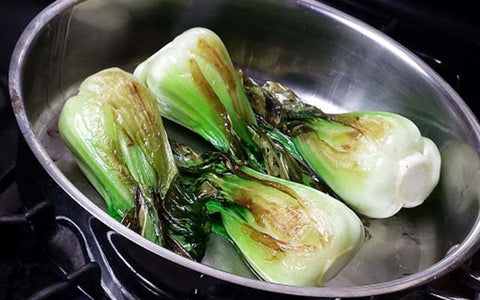 Image of Under adult supervision, in a deep sauté pan, carefully heat up the oil over a medium flame, then sauté four baby bok choy at a time until slightly browned (about 2 minutes on each side). Be careful to not overcrowd the pan. Transfer each batch of four to a plate and keep warm until ready to serve