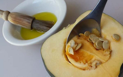 Image of Scoop out seeds of each acorn squash half, then rub the inside of each half with the olive oil. Place each half, cut side up, on a baking sheet and then hand off to the supervising adult for the initial bake