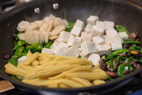 Image of adding in baby corn, water chestnuts, chinese long beans, and tofu