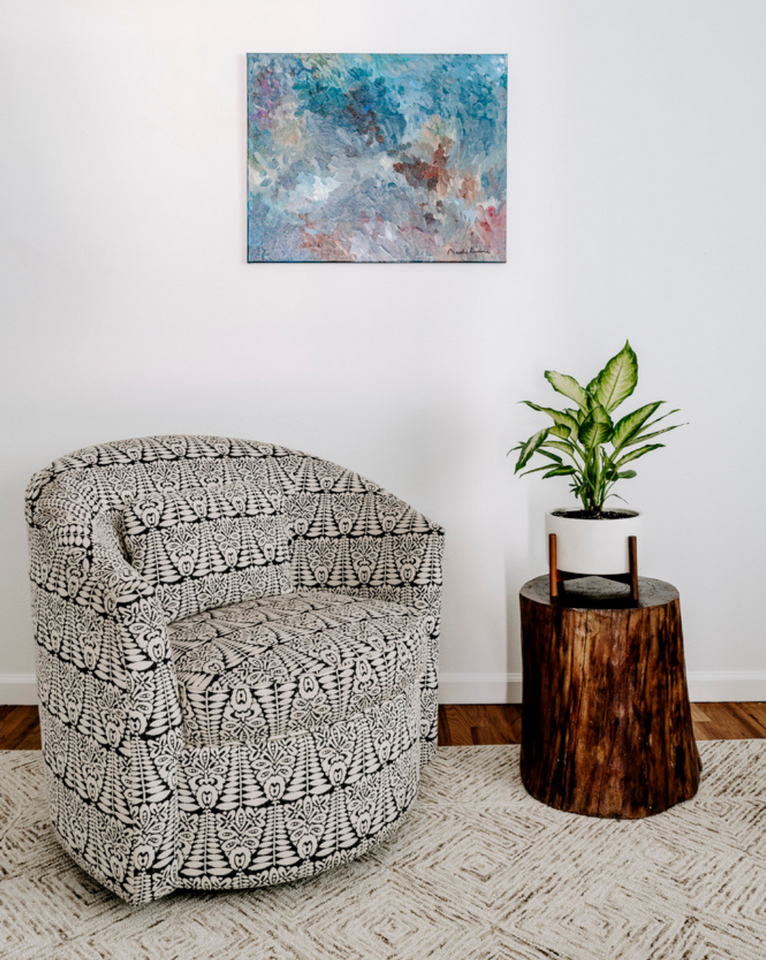 <img src="reupholsteredchairsottomansmore_ouroriginalspage.png" alt="Black and white ikat swivel chair by Rogala Design with colorful art and stump side table with plant ">