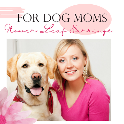 woman wearing pink shirt and long flower statement earrings while posing next to a dog