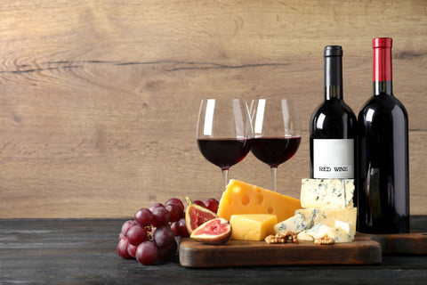 cheeses, fruits and wine on table against wooden background