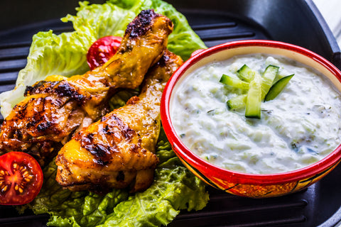 Tzatziki sauce or dressing with grilled chicken legs and fresh vegetable,lettuce salad and cherry tomatoes