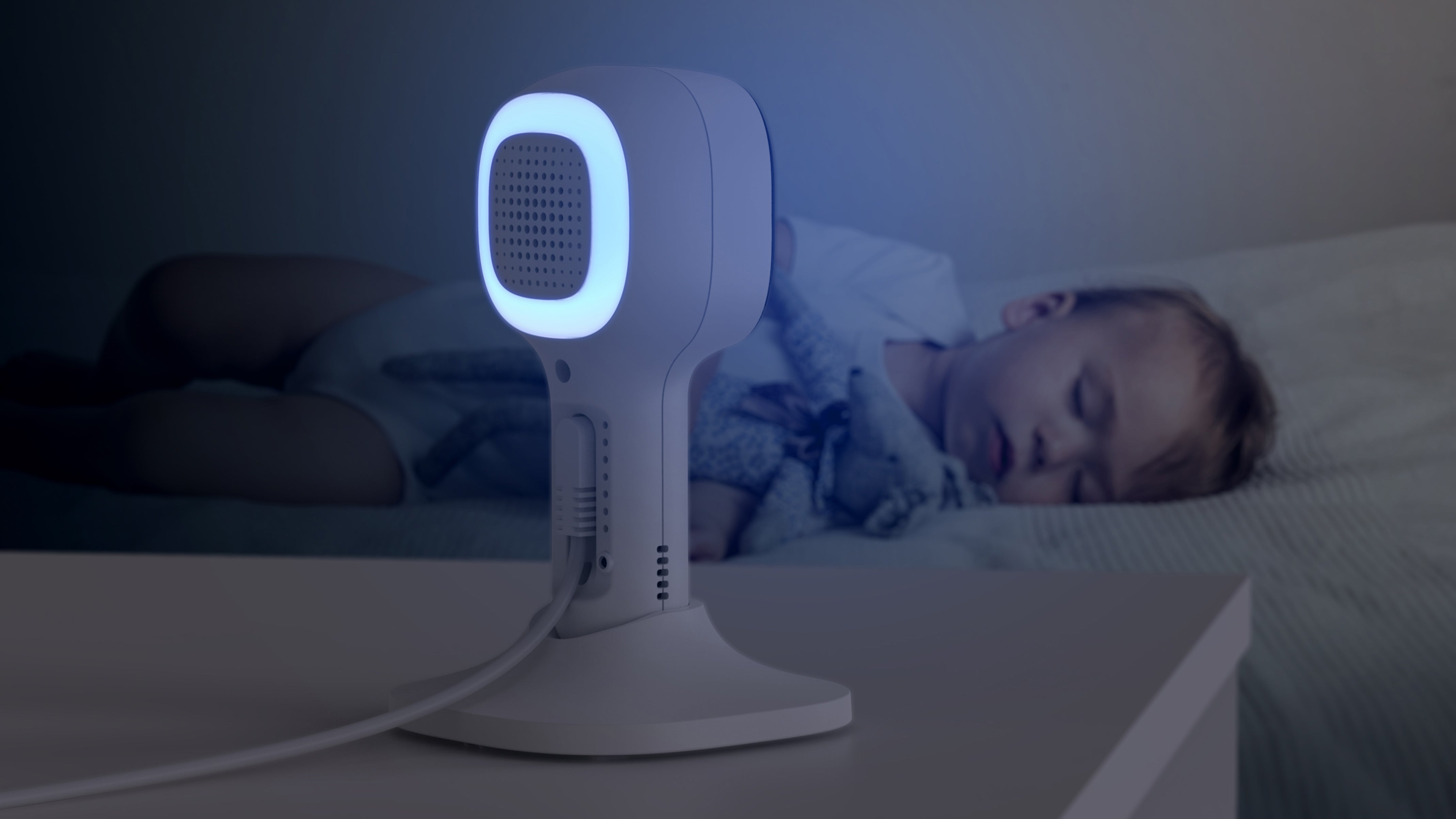 Baby sleeping in bed with a baby monitor.