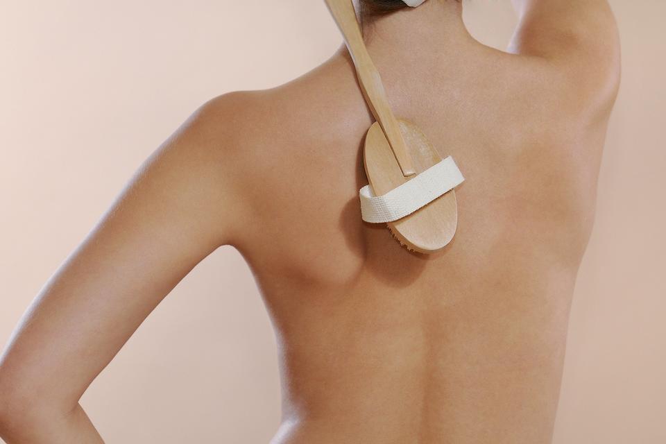 A woman dry skin brushing her back 