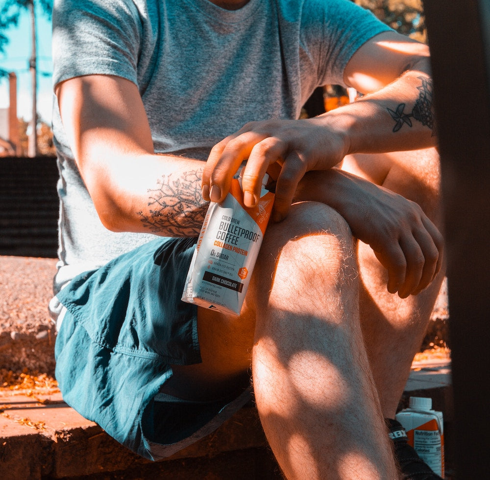 man sitting and holding a bottle of bulletproof coffee