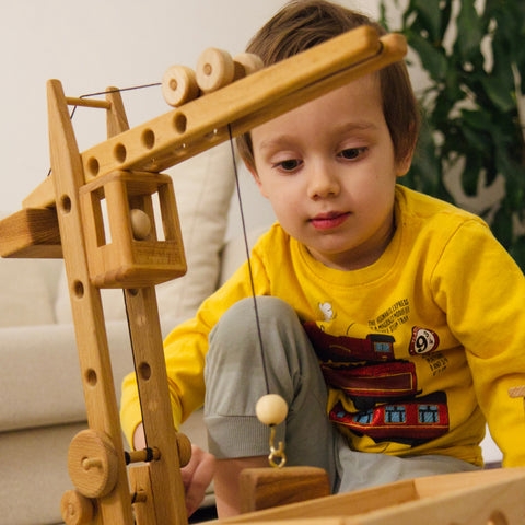 child playing with wooden crane