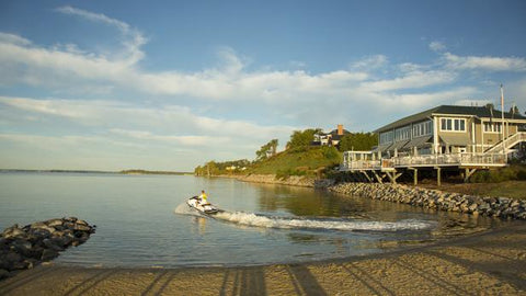 Photo of Person Jet Skiing From Shore with House in Background