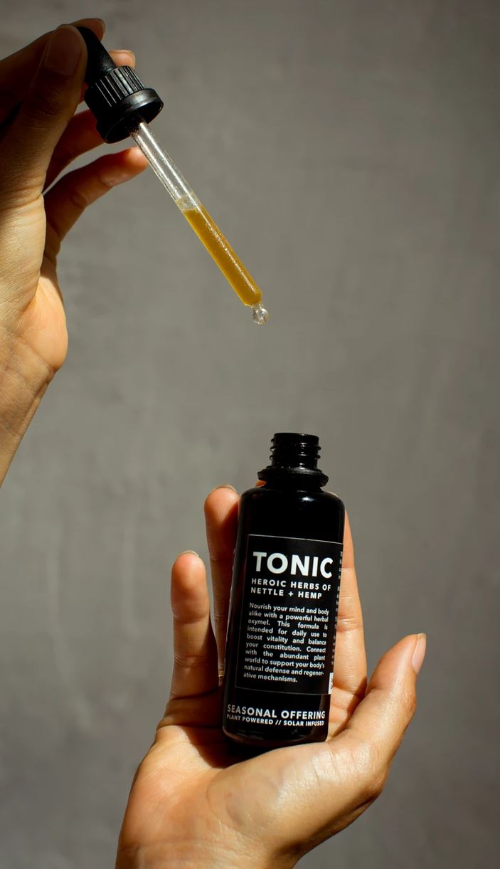 hand holding cbd natural tonic and dropper hemp skincare