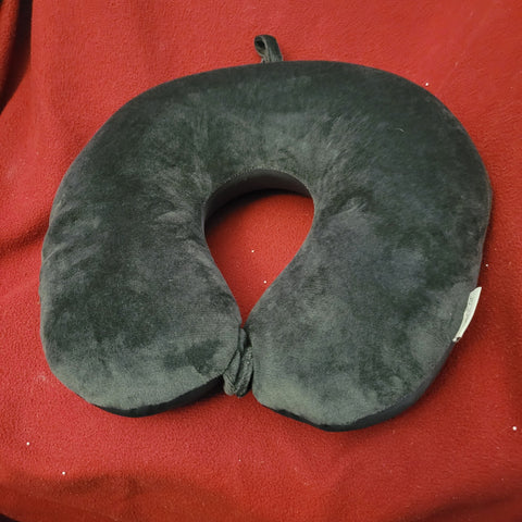 Gray, soft neck pillow with a button clasp sitting on a red cloth.