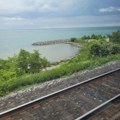 Pretty view of light blue water of Lake Ontario alongside the train tracks.