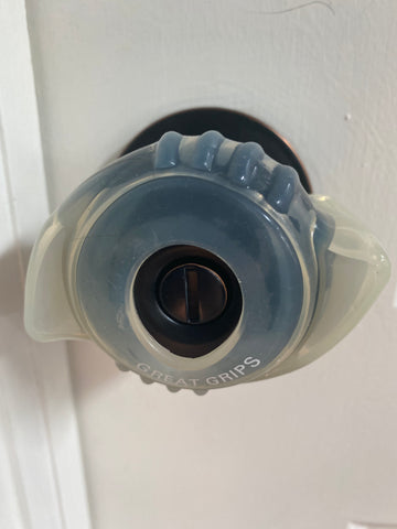 Clear Able Life EZ grip with small "wings" on either side attached to a round black door handle.