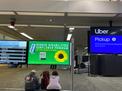 A screen at an airport that says "hidden disabilities sunflower program" and has a picture of a sunflower