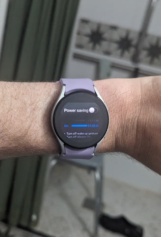 Smartwatch with circular face and purple band on a person's wrist.