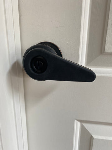 Black rubber Sammons Preson extension handle, which creates a lever on a round black doorknob.