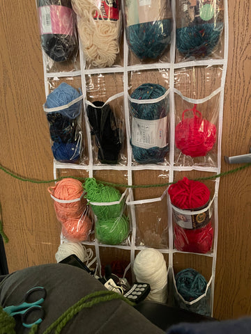 Green yarn stretching across a door from the hinge to the handle, over an organizer full of yarn.