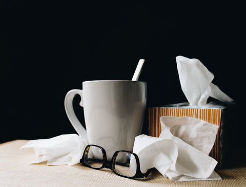 Tissues with coffee cup and glasses on bedside table