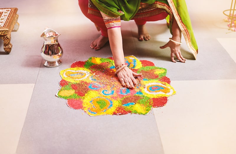 An intricate Rangoli pattern being created on the floor of a home