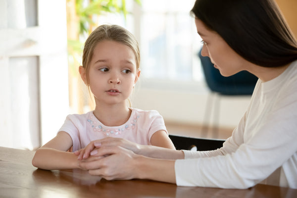 Young child looking upset and talking to female adult