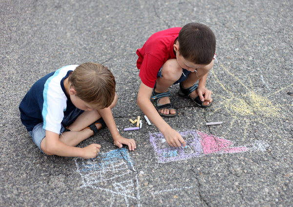 Two boys drawing with chalk on the pavement