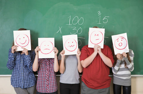  Children holding up expressions cards by a blackboard