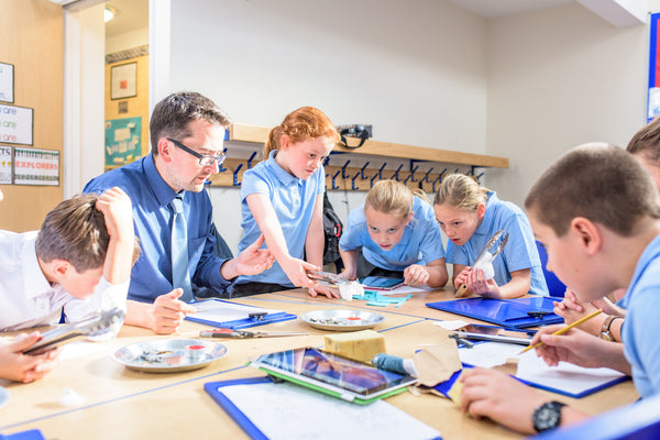 A teacher and group of primary school children working collaboratively