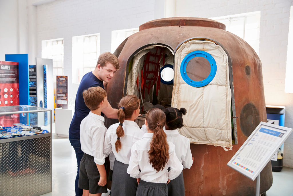 Kids and teacher look at a space capsule at a science centre