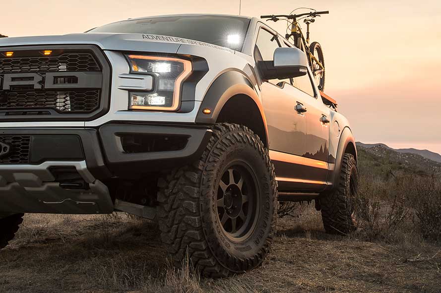 2019 Ford Raptor at sunset with a mountain bike and overland tent in the truck bed