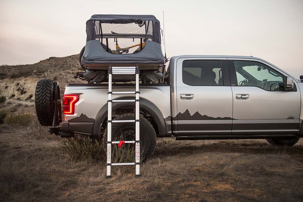 Side view of a 2019 ASV Ford Raptor with Tepui roof tent open on a mountain at sunset