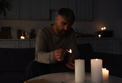 A man lighting candlesticks during a power outage.