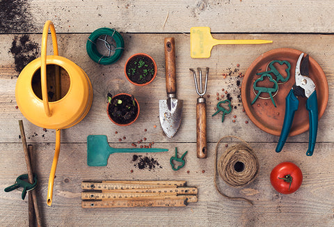 A wood table with an array of gardening tools spread out.