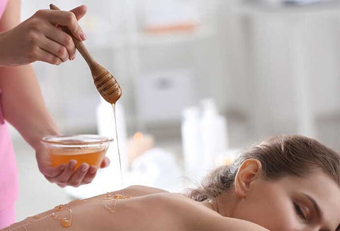 A masseuse dripping honey onto a woman's back for a relaxing massage.