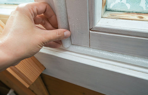 A hand repairing a window with a leak on the side.