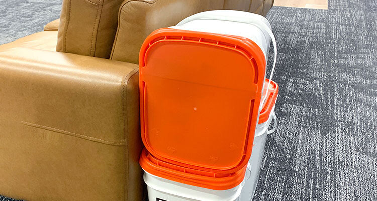 emergency food buckets stacked behind a couch